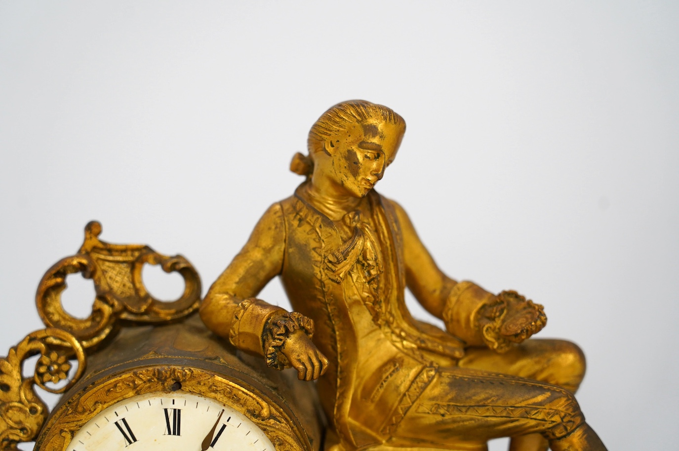 A 19th century figurative ormolu mantel clock, with floral porcelain panels, on stand with key and pendulum, stand approximately 39cm wide. Condition - clock dial cracked, clock untested as working